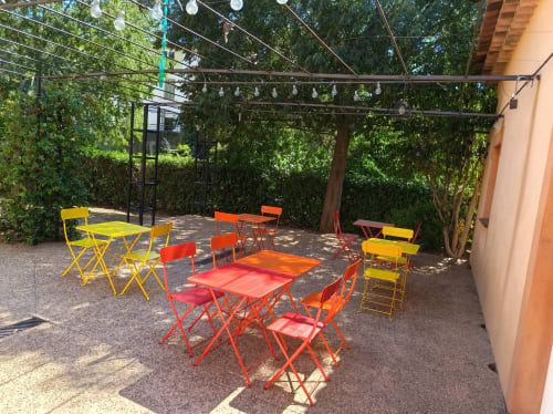 Espace de restauration extérieur coloré à l'hôtel Le Clos du Thoronet avec tables rouges, jaunes et orange sous pergola en Provence
