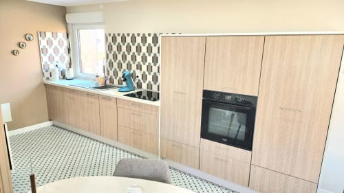 Cuisine moderne avec armoires en bois clair, four noir et dosseret à motifs à la villa Ô de Mer à Sangatte