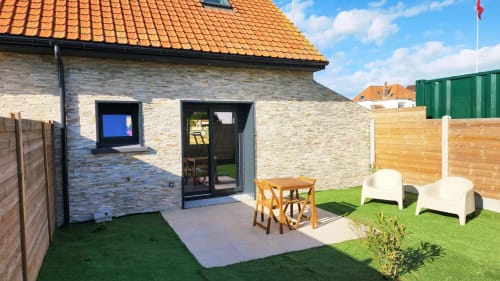 Vue du jardin de la villa Ô de Mer avec terrasse, coin détente et extension en brique moderne à Sangatte