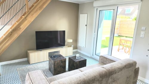 Séjour moderne de la villa Ô de Mer avec vue sur le jardin, canapé, TV, escalier bois et portes-fenêtres sur patio à Sangatte