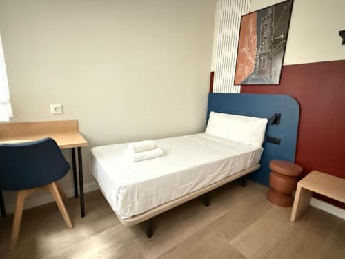 Modern hostel bedroom at Groma Rooms in Zaragoza with single bed, desk, chair, and shared bath facilities
