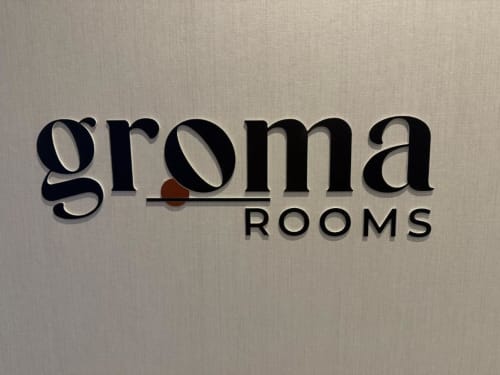 Groma Rooms hostel sign in Zaragoza displaying black serif typography on beige wall