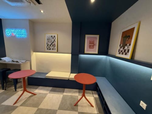 Groma Rooms hostel double room in Zaragoza with shared seating area, red tables, and modern neon signage