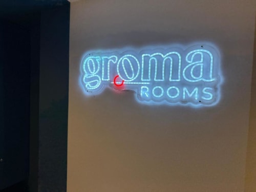 Groma Rooms neon sign at hostel entrance in Zaragoza, Spain