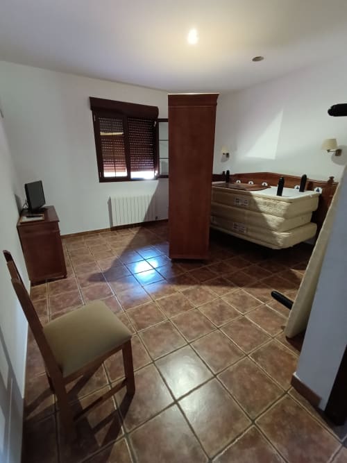 Habitación espaciosa en Hospedería Puerta a los Cahorros en Monachil con piso de azulejos, muebles de madera y mesa de juegos.