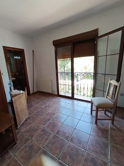 Dormitorio espacioso en la Hospedería Puerta a los Cahorros de Monachil con acceso a terraza y suelo de baldosa marrón