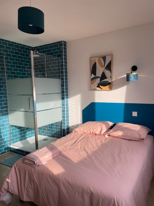 Chambre moderne à Mattbnb à Metz avec literie rose, douche carrelage bleu-vert, mur d'accent bleu et lumière naturelle