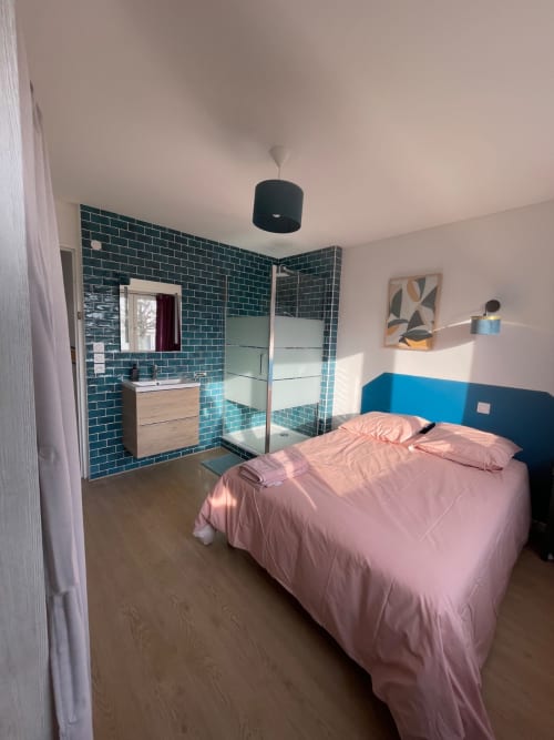Chambre moderne Mattbnb Metz avec parure rose, tête de lit bleu et salle de bain attenante carrelage turquoise