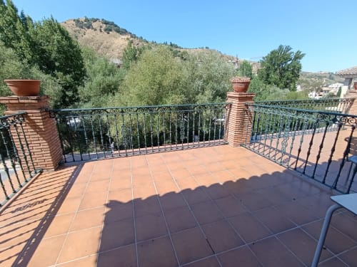 Terraza de teracota con barandilla de hierro forjado con vistas a olivos y montañas en Hospedería Puerta a los Cahorros