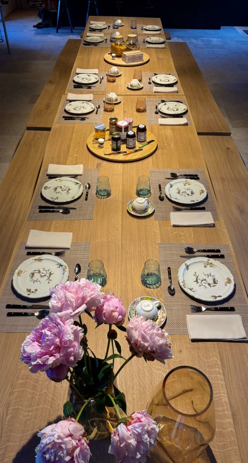 Grande table de salle à manger en bois élégante à Cloffy B&B, dressée avec soin, pivoines roses et bouteilles de vin pour une expérience gastronomique raffinée