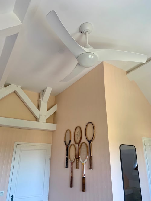 Ventilateur de plafond blanc dans la chambre Terracotta du Logis de la chouette à Baugé en Anjou, avec raquettes de tennis sur mur pêche