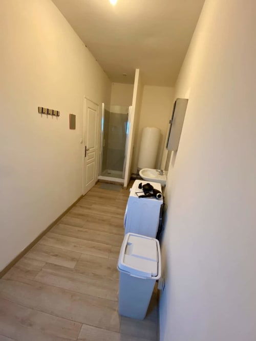 Couloir de salle de bain étroit aux Business Apparts Caudry avec rangements et douche