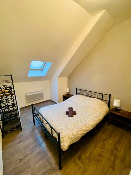 Chambre mansardée lumineuse avec velux, lit en fer forgé, plancher bois et mobilier moderne à Business Apparts Caudry.