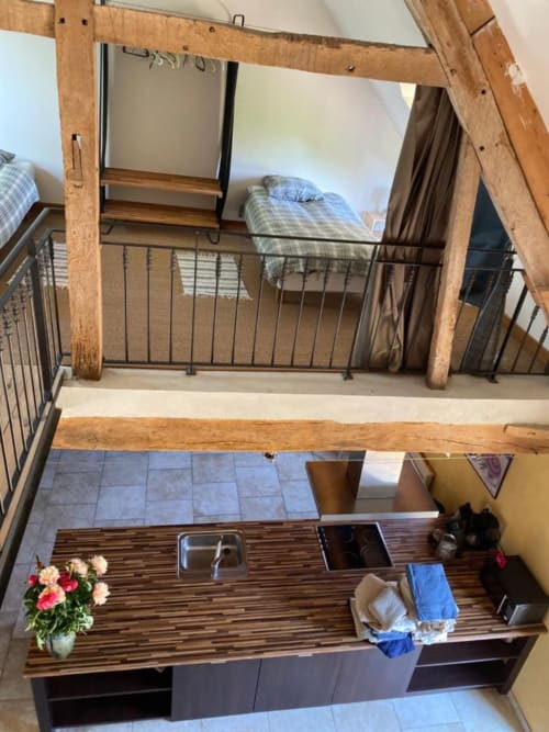 Chambre en mezzanine aux poutres apparentes dominant la cuisine aux Gîtes de Cormenin, Saint-Hilaire-sur-Puiseaux