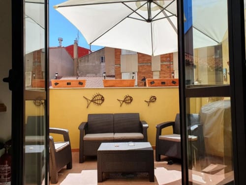 Terraza en la azotea del albergue Só Por Hoje en Astorga con mobiliario de mimbre, paredes amarillas y vistas de la ciudad