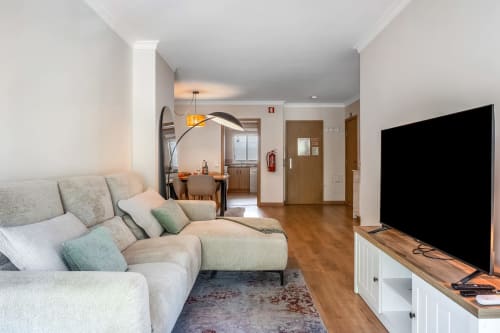 Sala de estar moderna em apartamento com sofá bege, área de refeições e TV de ecrã plano na Atlantic Places, Albufeira