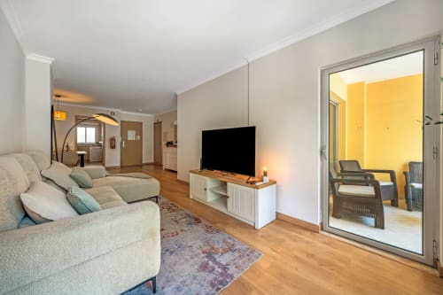 Sala de estar moderna com assentos confortáveis, TV, pisos de madeira e acesso a sala com paredes amarelas no Atlantic