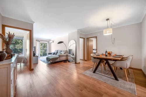 Sala de estar espaçosa no Atlantic Places, Albufeira, com mesa de jantar, sofá moderno e vista para o jardim