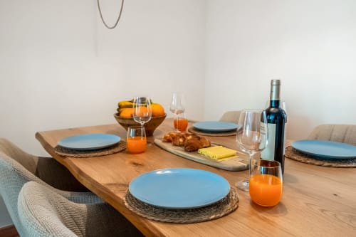 Elegante configuração de refeição no Atlantic Places Albufeira com pratos azuis, sumo de laranja, vinho e croissants no The Quiet Nest