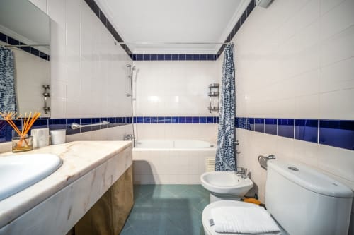 Casa de banho moderna no apartamento The Quiet Nest em Atlantic Places, Albufeira, com detalhes em azulejo azul e lavatório em mármore