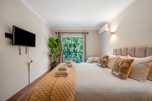 Suíte espaçosa em Atlantic Places, Albufeira, com vista para jardim, roupa de cama bege, TV de parede e comodidades modernas