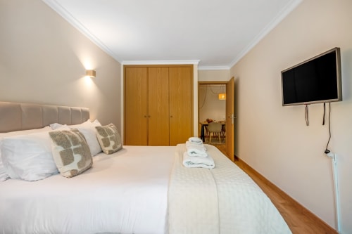Quarto moderno em Atlantic Places Albufeira com cama queen, guarda-roupa em madeira, TV e vista para jardim