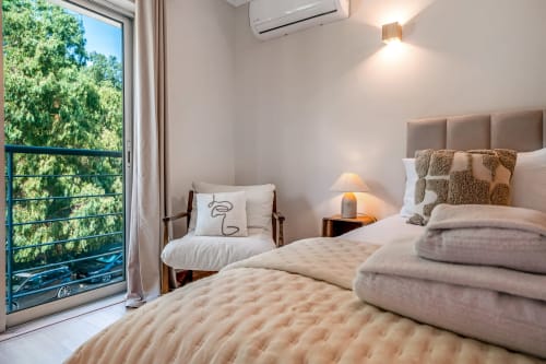 Quarto iluminado no Atlantic Places Albufeira com vista para o jardim, cama de casal, poltrona e acesso à varanda