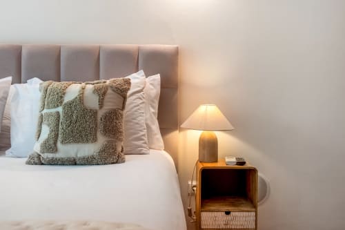 Quarto aconchegante no Atlantic Places Albufeira com cabeceira capitonada, almofadas texturizadas e luminária morna na mesa de cabeceira