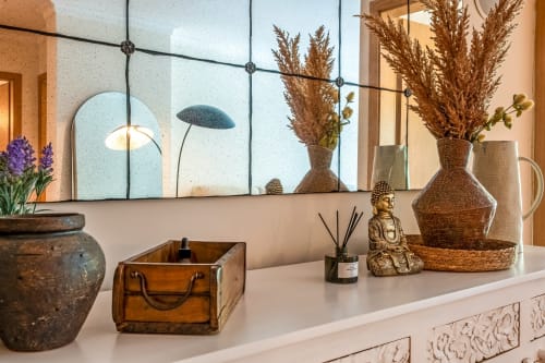 Cômoda elegante com grama-das-pampas, vasos trançados e peças decorativas no apartamento Atlantic Places em Albufeira