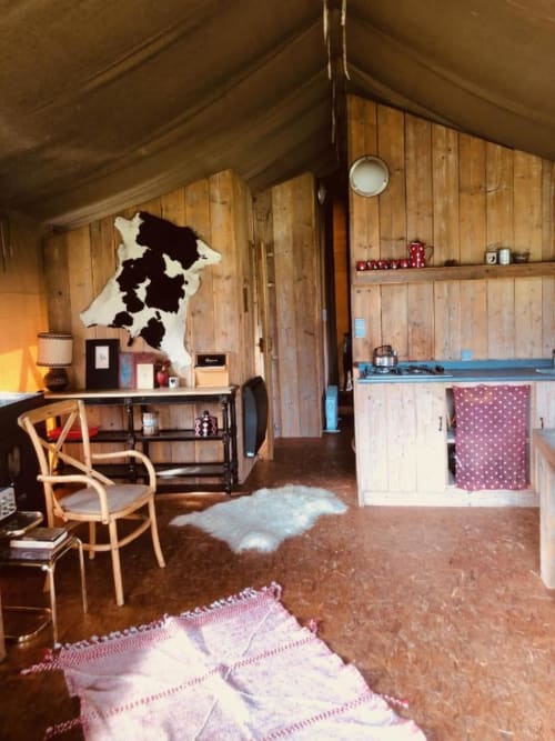 Intérieur confortable de glamping aux Gîtes de Cormenin : murs en bois, cuisine aménagée, bureau et mobilier rustique