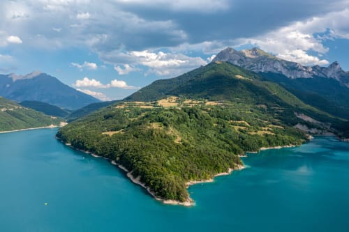 Lac alpin turquoise entouré de montagnes boisées près de Corps, destination hôtelière en France