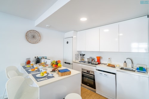 Cocina blanca moderna en Alhaurín Loft con comedor, electrodomésticos de acero inoxidable y frutas frescas en la encimera