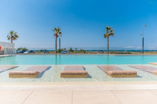 Piscina turquesa frente al mar con palmeras y vistas al océano en Alhaurín Loft, apartamento de lujo en España
