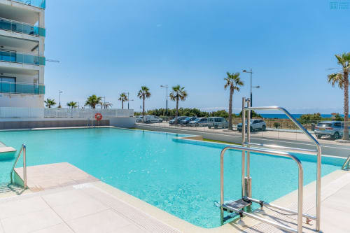 Piscina turquesa con barandillas metálicas en Alhaurín Loft, palmeras, aparcamiento y vistas al mar Mediterráneo