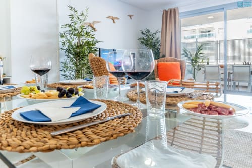 Elegante configuración de comedor en el Apartamento de Lujo Beachfront de Maruchis con copas de vino, montaje de mesa y vistas al mar