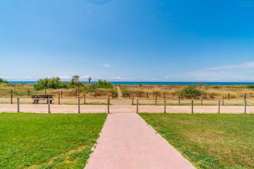 Paseo frente al mar con césped impecable, barandillas de madera y vistas al mar en Alhaurín de la Torre.