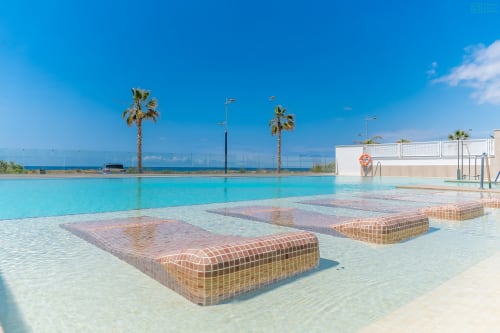 Piscina de lujo frente al mar en Alhaurín Loft con agua turquesa, tumbonas, palmeras y vistas al Mediterráneo