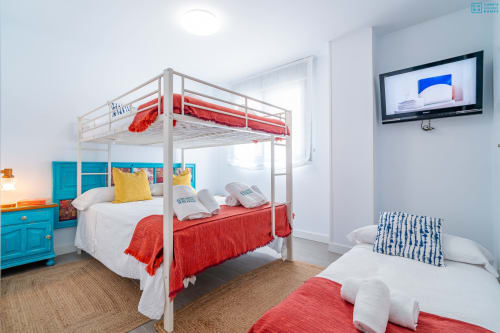 Dormitorio infantil luminoso con cama con dosel rojo, litera blanca, muebles turquesas y TV en Alhaurín Loft City Center