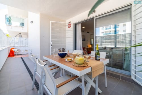 Moderno comedor en apartamento con vista al mar, terraza, mesa blanca, cocina y acceso a balcón en Alhaurín de la Torre