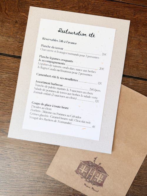 Menu d'été de Maison Mansel B&B avec plats à l'assiette et tarifs sur papier kraft, devant le manoir