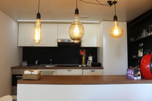 Cucina moderna con luci a sospensione, armadi bianchi, alzatale nera e piano in legno a La Terrazza sul Ricetto