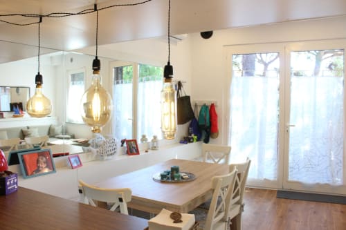 Zona pranzo loft moderno sulla spiaggia con lampade a sospensione, tavolo in legno e vista sul mare a La Terrazza sul Ricetto a Marina di