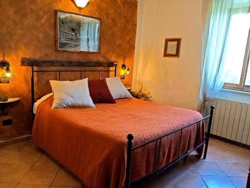 Cozy bedroom at I Castagnini B&B in Montecatini Val di Cecina with orange walls, metal bed frame, and warm lighting