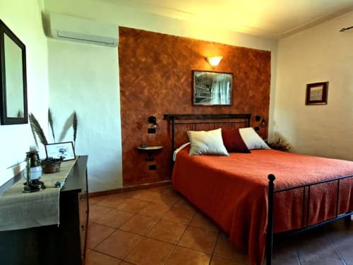 Limone cottage bedroom at I Castagnini B&B in Montecatini Val di Cecina with terracotta accent wall and red bedding