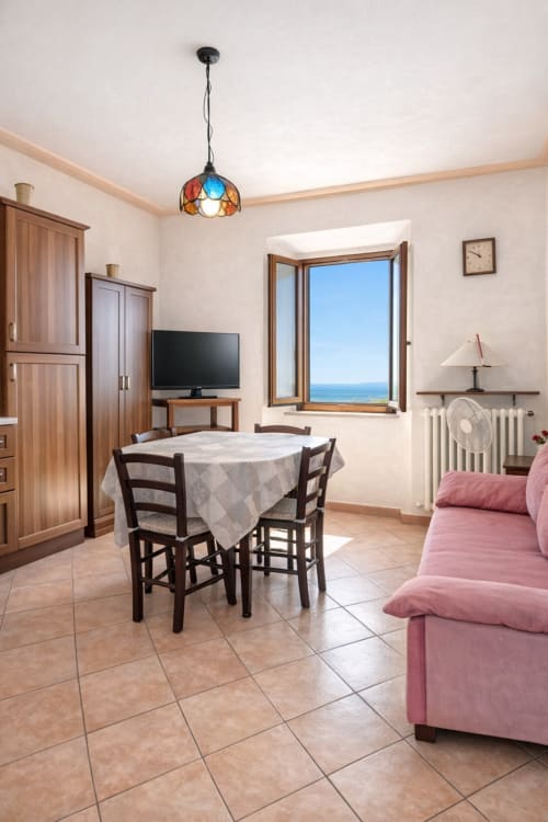 Bright cottage apartment at I Castagnini with sea view, dining table, pink sofa, and wood furnishings in Montecatini Val di
