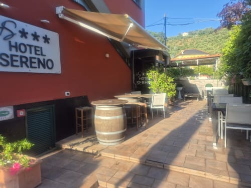 Terrazza dell'Hotel Sereno a Sestri Levante con sedute a botte, tenda e vista sulle colline