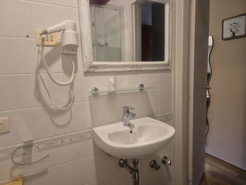 Bagno moderno con lavandino bianco, specchio, asciugacapelli a parete e mensola decorativa nell'appartamento hotel di Sestri Levante