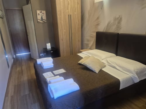 Camera d'hotel moderna a Seaside ENNE a Sestri Levante con letto scuro, cuscini bianchi, armadio in legno e vista sulla città