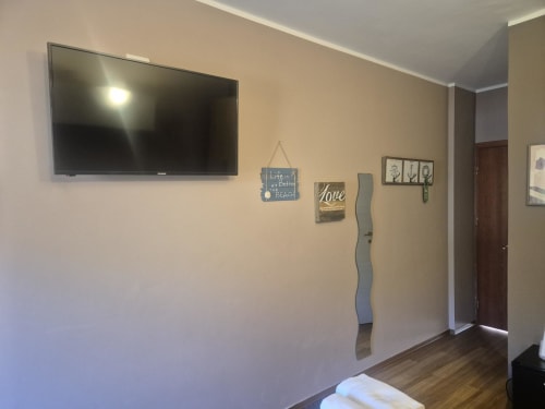 Camera moderna dell'Hotel Seaside Sestri Levante con TV a parete, arredamento marino e pavimenti in legno