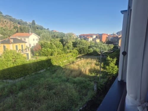 Vista dal balcone dell'appartamento Hotel Sereno sul villaggio di Sestri Levante con edifici colorati, colline verdi e valle fluviale